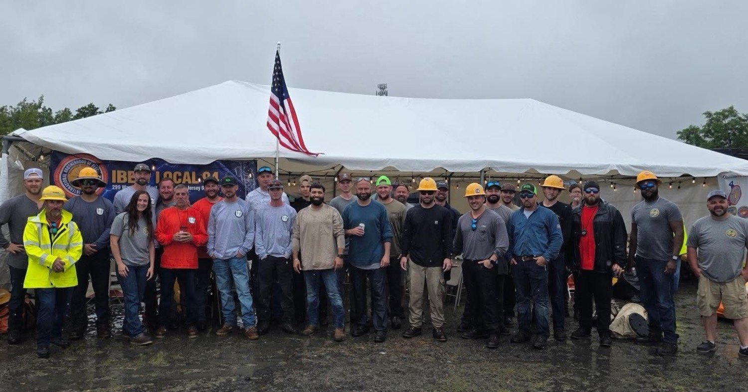 Local 94 members lined up under a white tent and an American flag